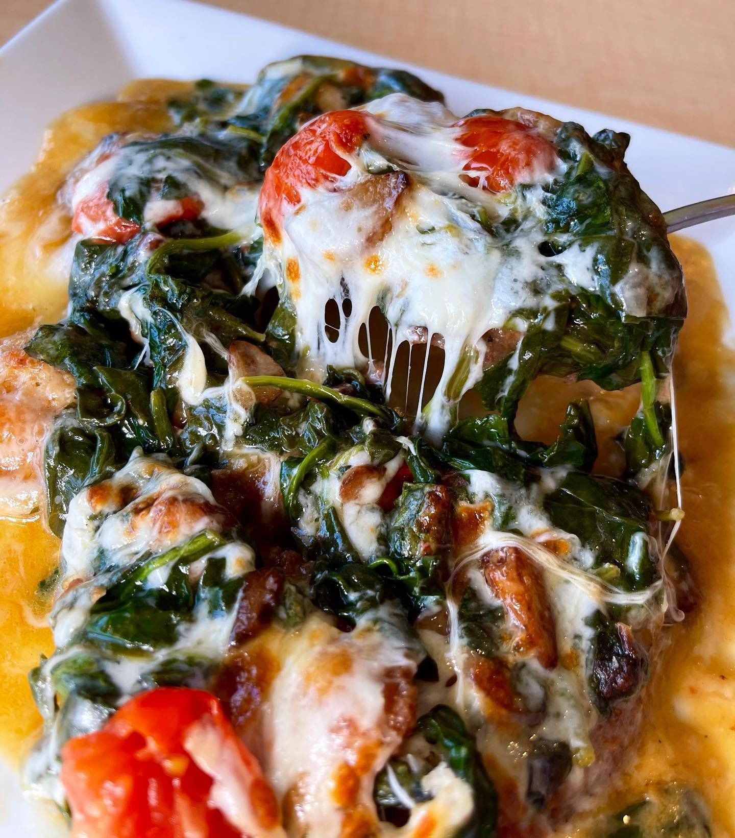 A close up of a plate of food with spinach tomatoes and cheese