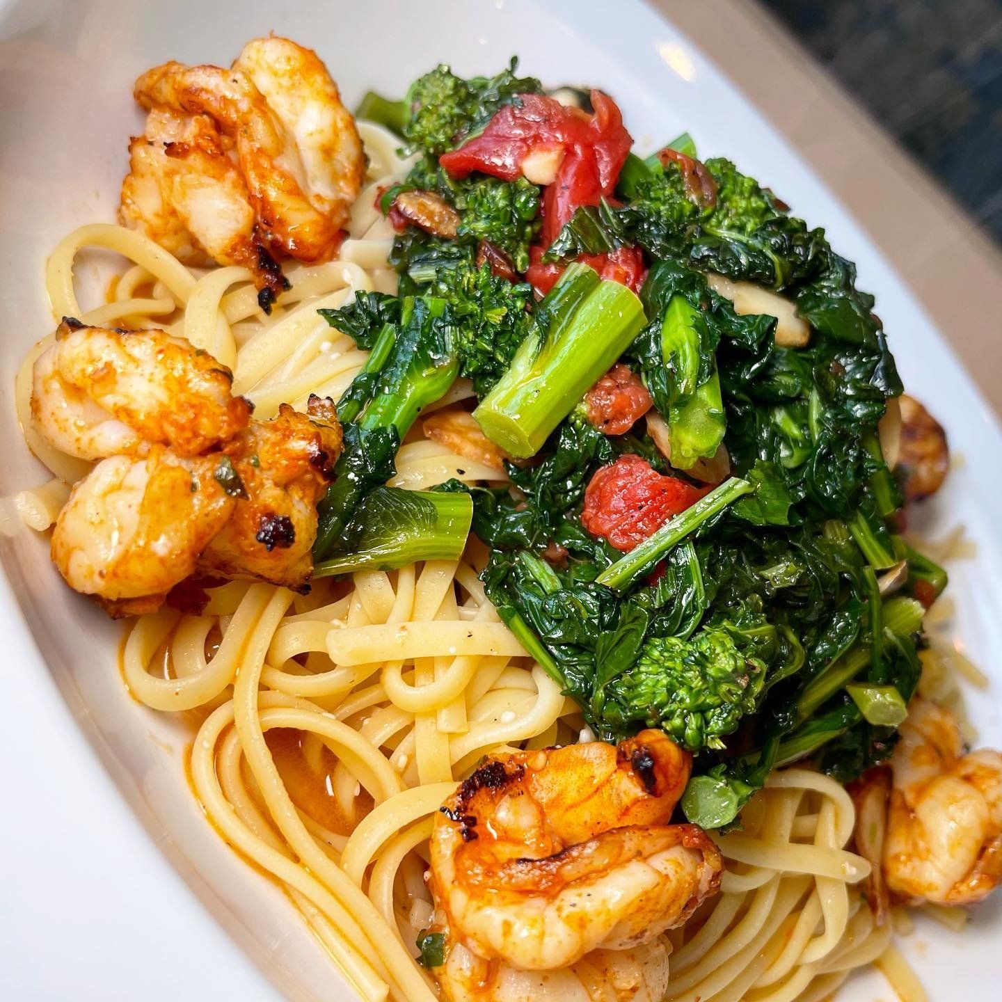 A plate of spaghetti with shrimp and broccoli on it