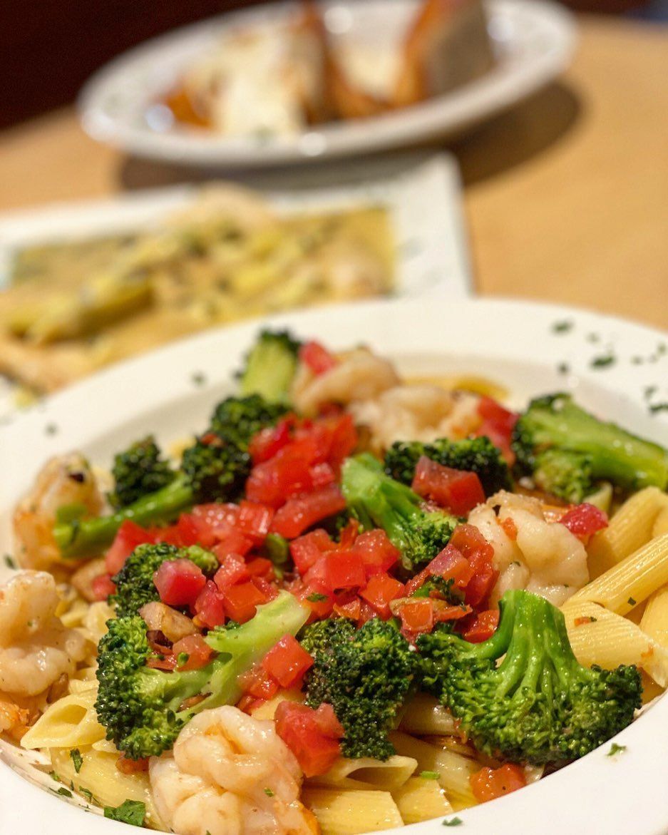 A bowl of pasta with broccoli and shrimp on a table