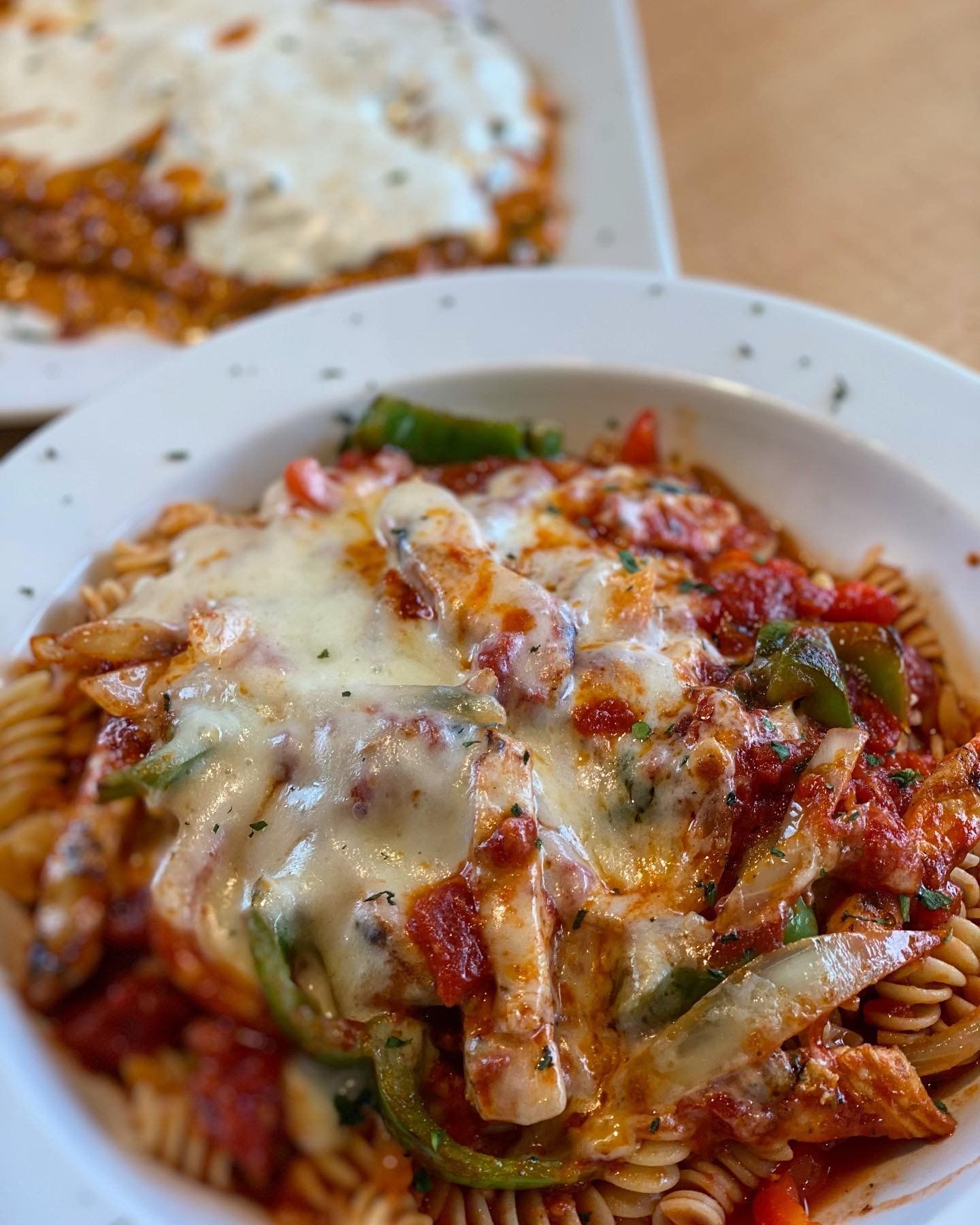 A close up of a plate of pasta with tomato sauce and cheese on a table.