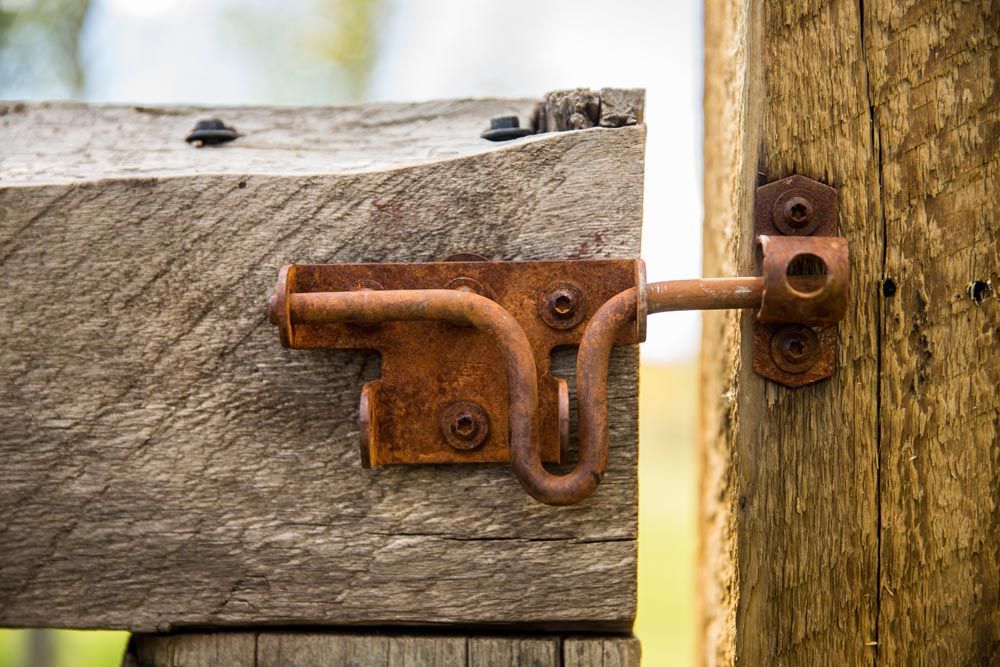 A rusty latch is attached to a wooden post.