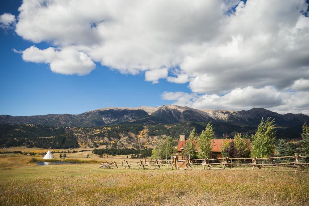A house in the middle of a field with mountains in the background.