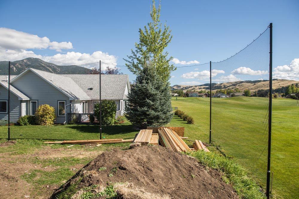 A pile of dirt is in front of a house and a golf course.