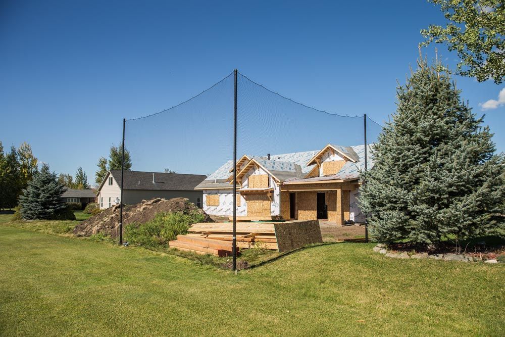 A house is being built in a backyard with a fence around it.