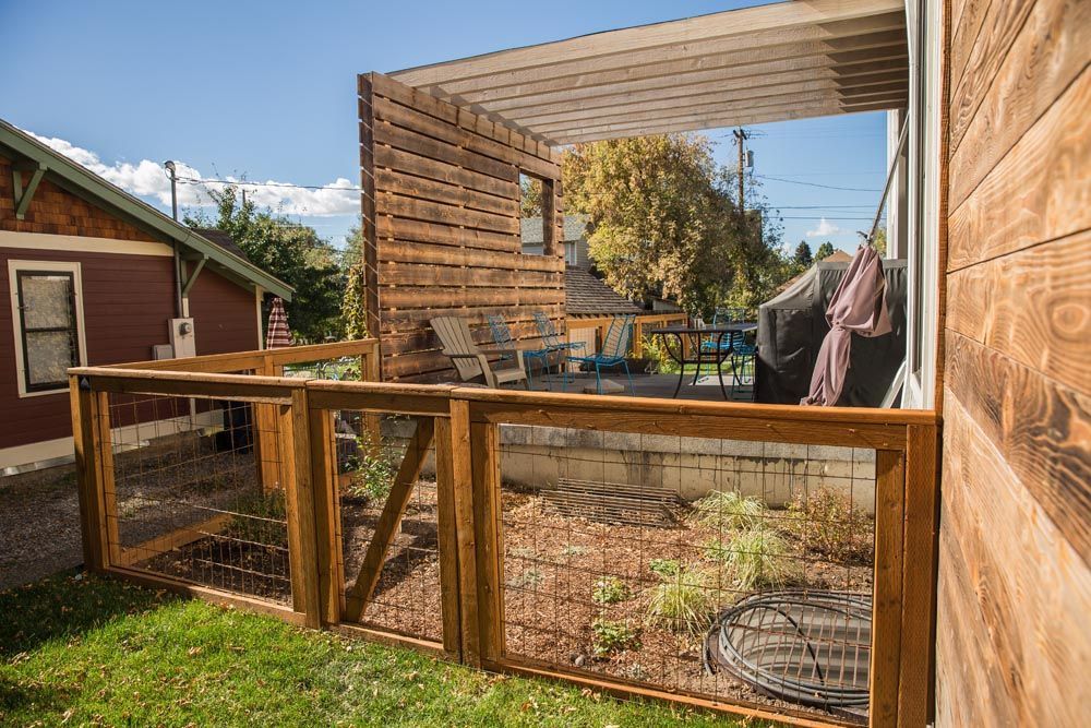 A wooden fence surrounds a backyard of a house.