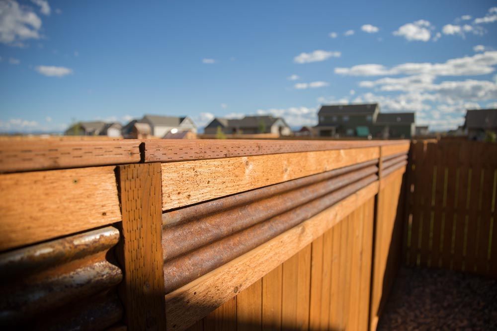 A close up of a wooden fence with a blue sky in the background.