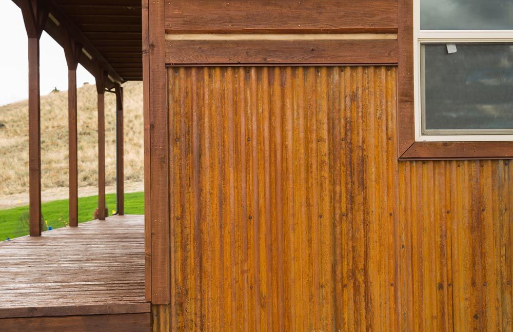 A wooden house with a porch and a window.
