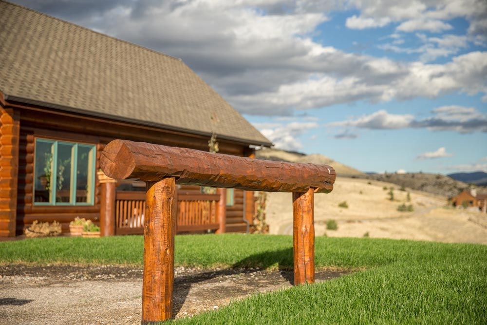 A log cabin with a wooden fence in front of it.