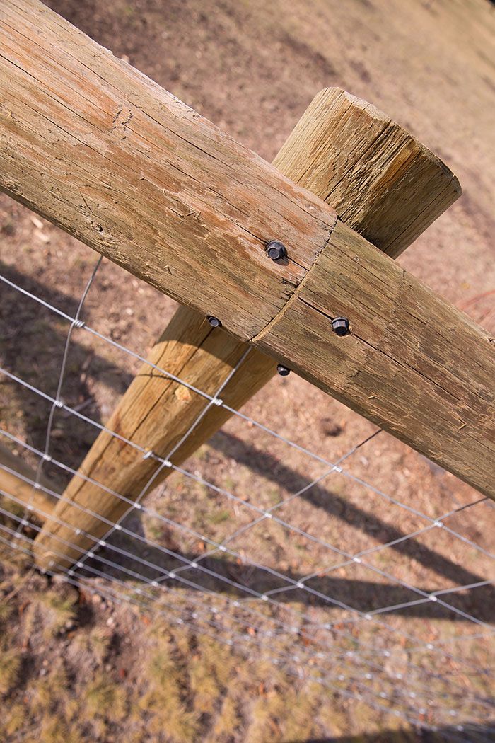A close up of a wooden fence with a wire fence attached to it.