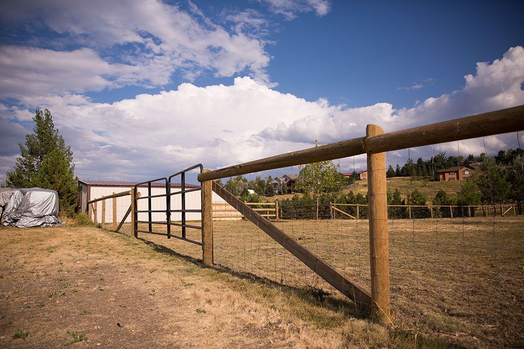 A wooden fence with a gate in the middle of a field.