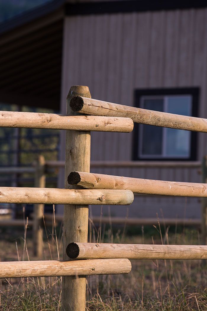 A wooden fence in front of a house in a field.