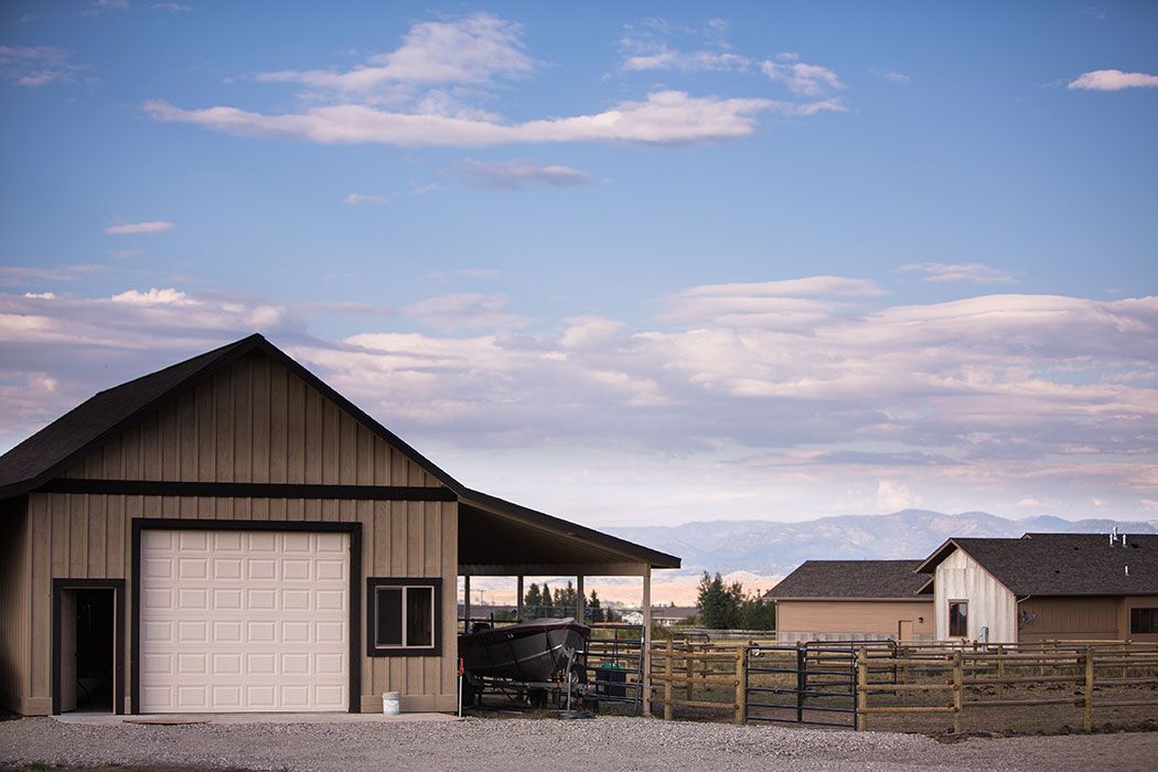 A house with a garage and a fence in front of it.