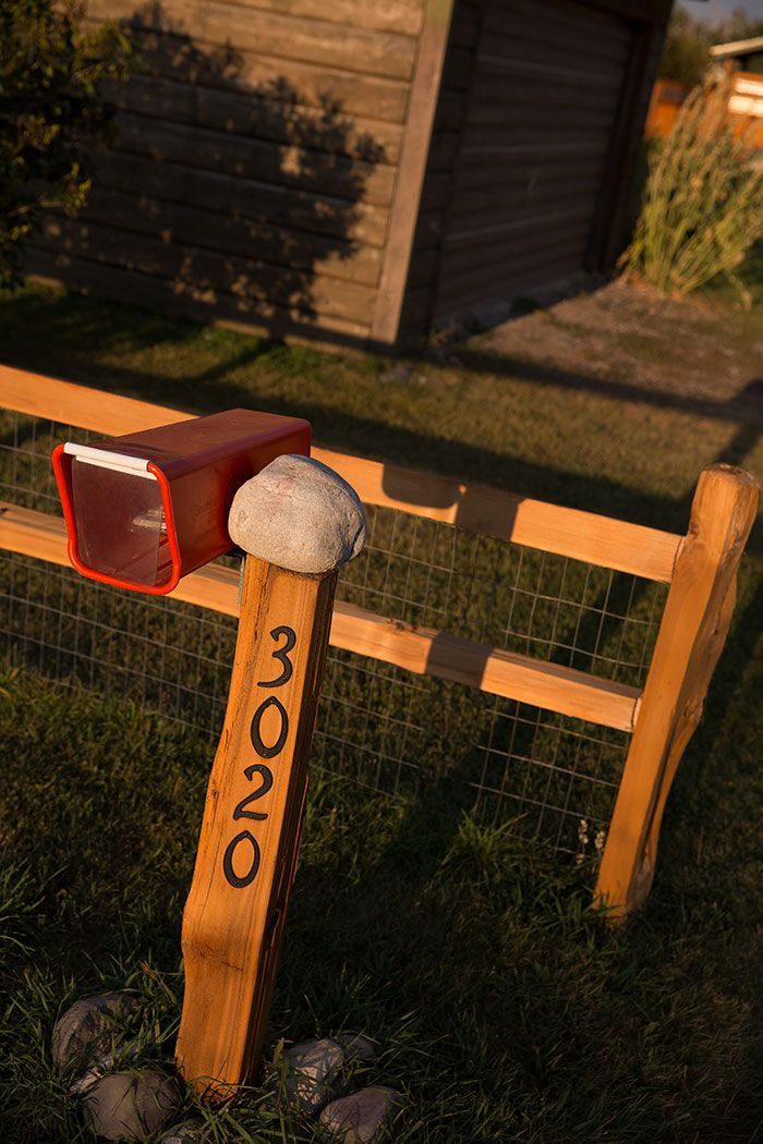 A mailbox is sitting on top of a wooden post next to a fence.
