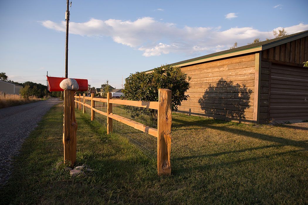 A wooden fence surrounds a mailbox in front of a garage.