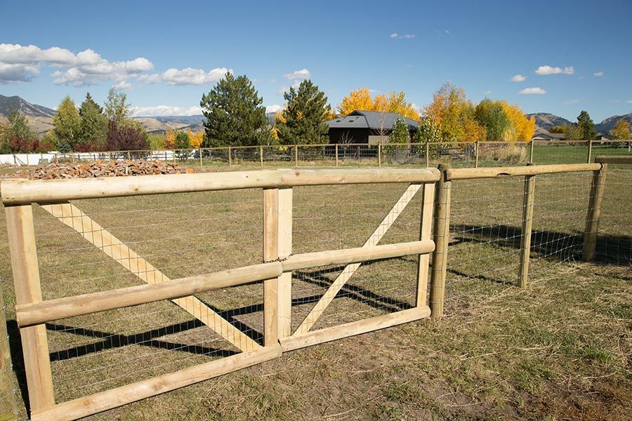A wooden fence in a field with a house in the background.