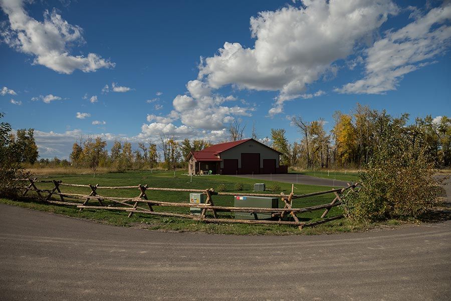 A barn with a red roof is behind a wooden fence.