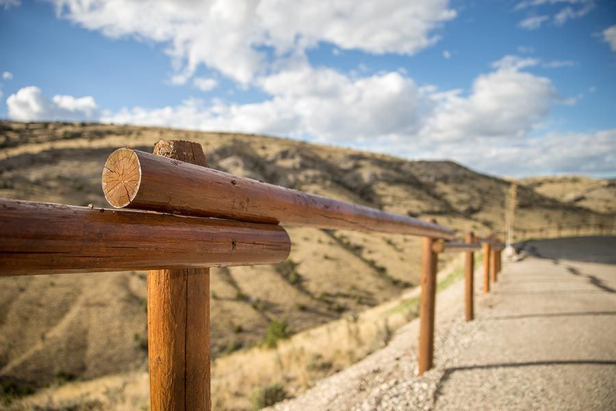 A wooden fence along a path with mountains in the background.