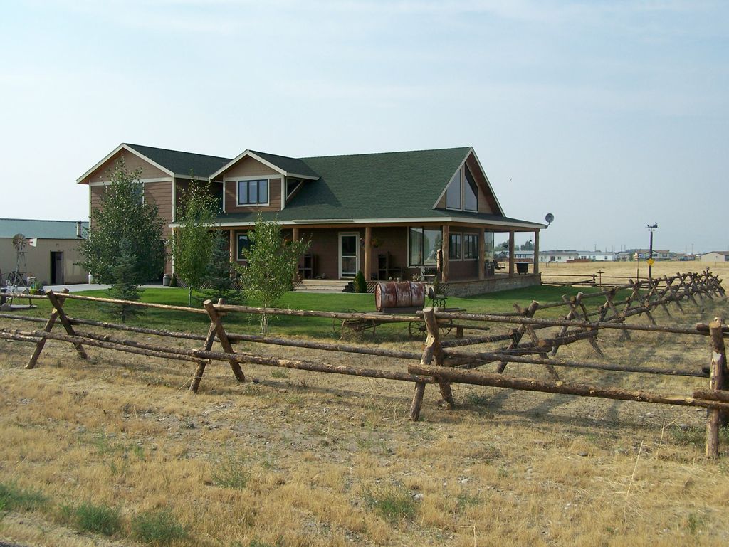 A house with a green roof is surrounded by a wooden fence.