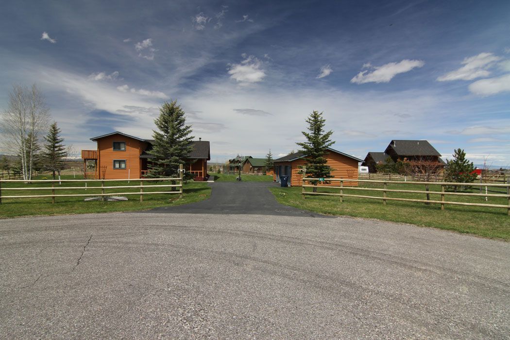 A dirt road leading to a row of houses with a wooden fence.