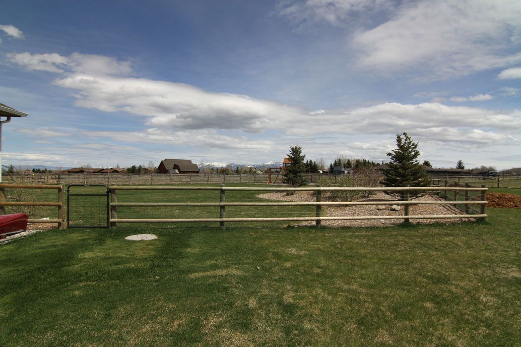 There is a wooden fence in the middle of a grassy field.