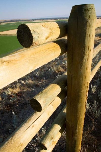 A close up of a wooden fence with a field in the background.