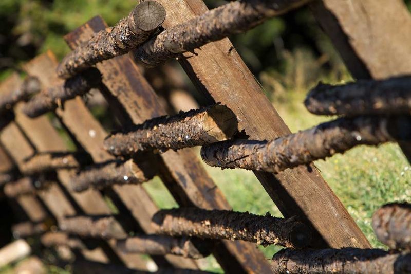 A close up of a wooden fence made of logs.