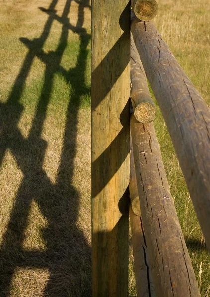 A wooden fence with a shadow on the ground.