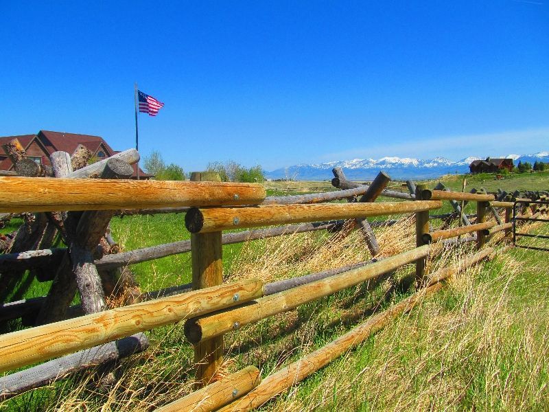 A wooden fence in a field with an american flag in the background.