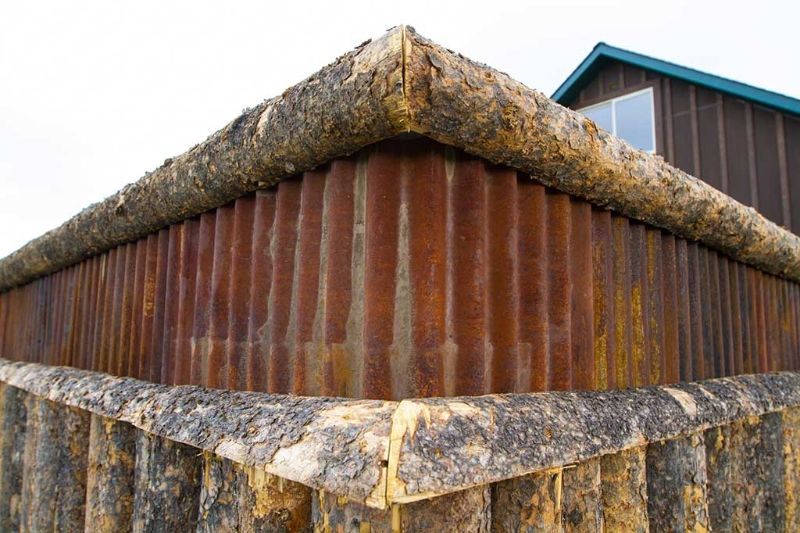 A rusty metal wall with a wooden fence around it.