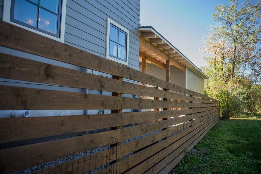 A wooden fence surrounds the side of a house.