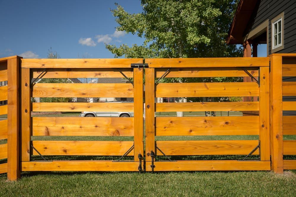 A wooden fence is sitting in the grass in front of a house.