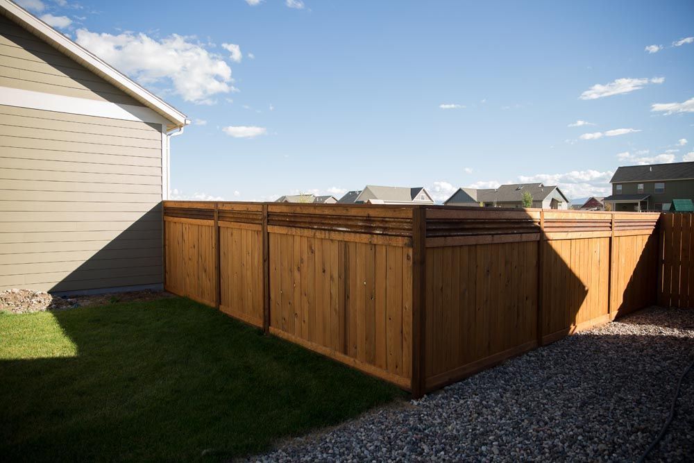 A wooden fence is in the backyard of a house.