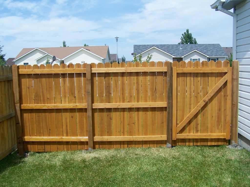 A wooden fence with a gate in the backyard of a house.