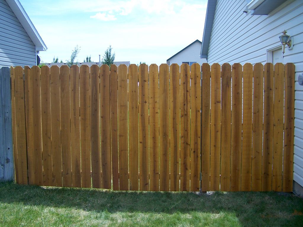 A wooden fence is in the backyard of a house.