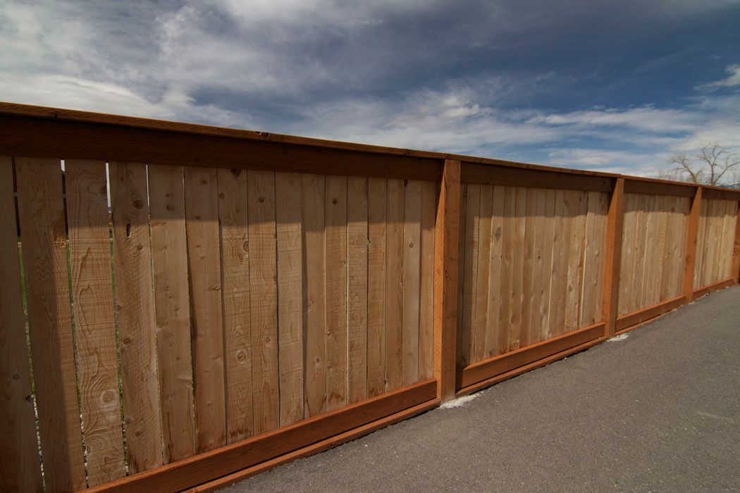 A wooden fence is sitting on the side of a road.