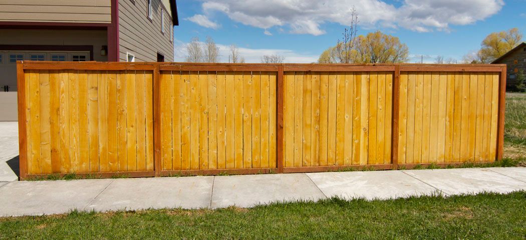 A wooden fence is sitting on the sidewalk in front of a house.