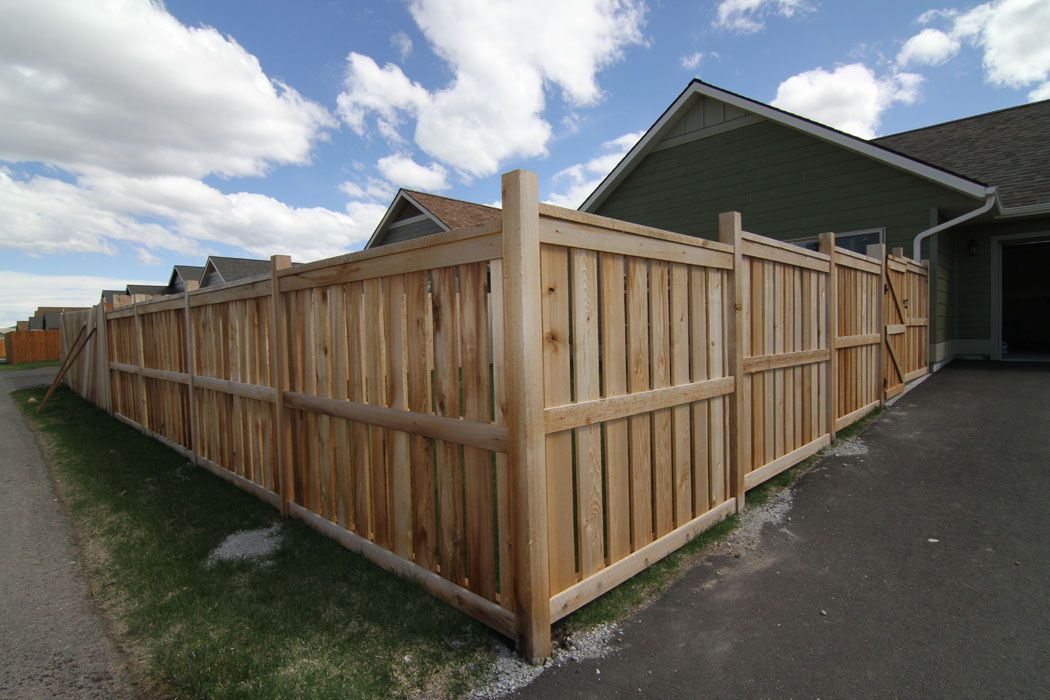 A wooden fence is surrounding a house in a residential area.