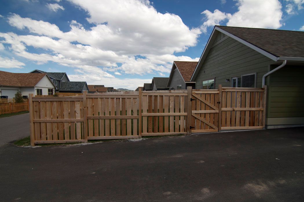 A wooden fence with a gate in front of a house.