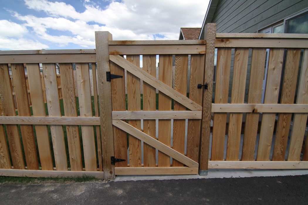 A wooden fence with a gate in front of a house.