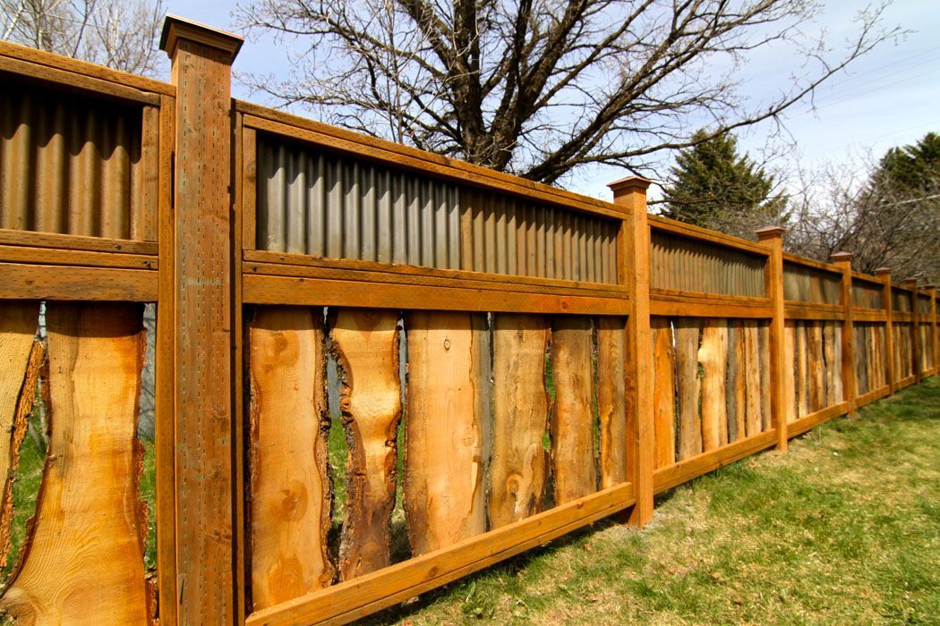 A wooden fence with a metal fence in the backyard.