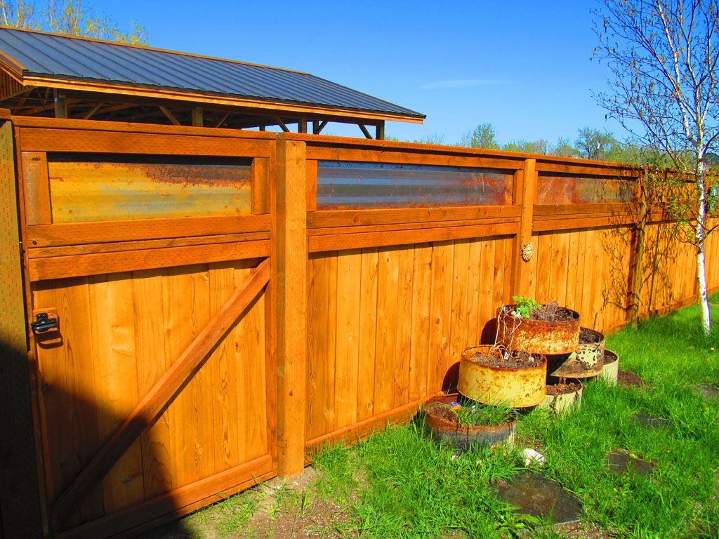 A wooden fence with a gate and a shed in the background.