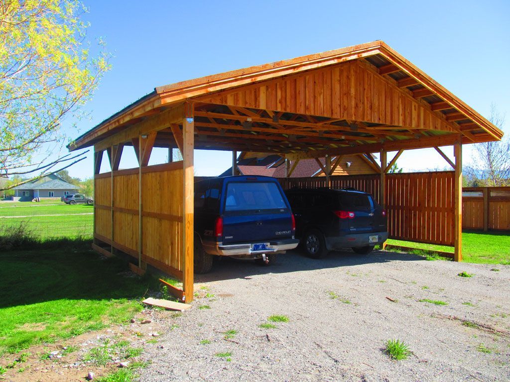 Two cars are parked under a wooden carport.