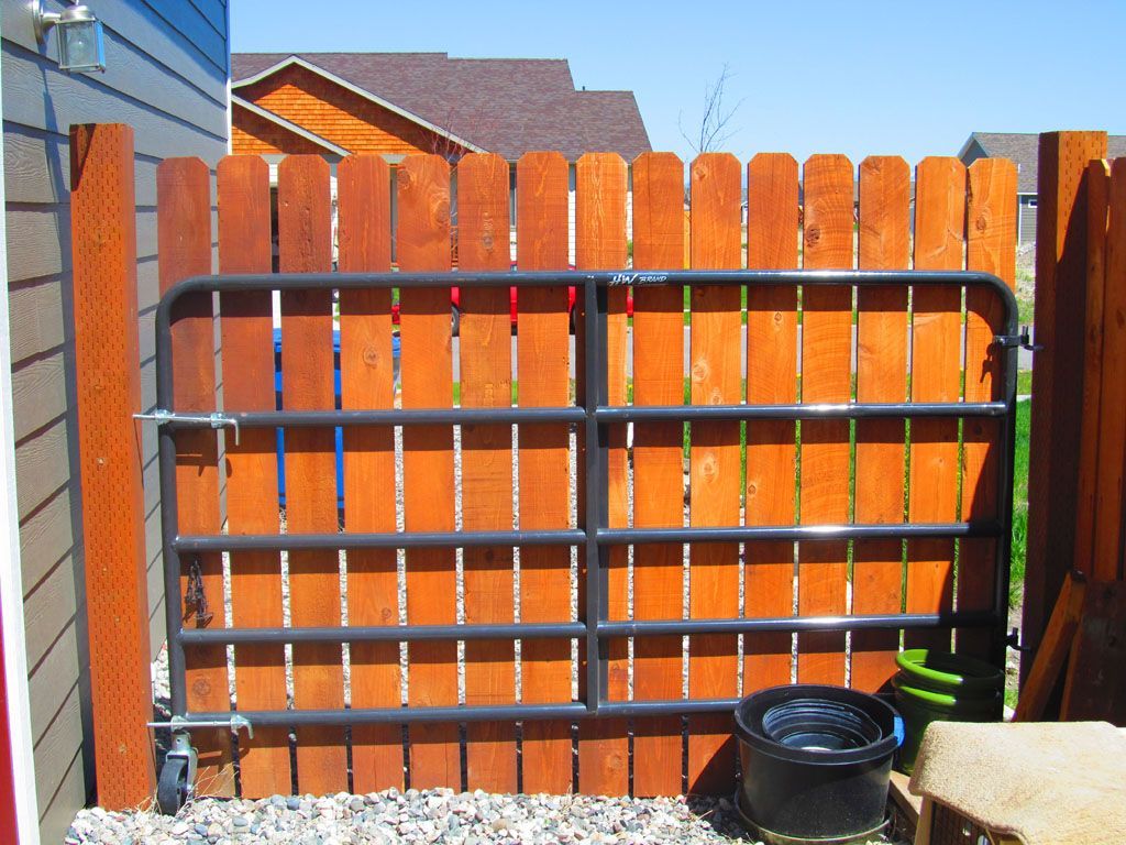 A wooden fence with a metal gate behind it.