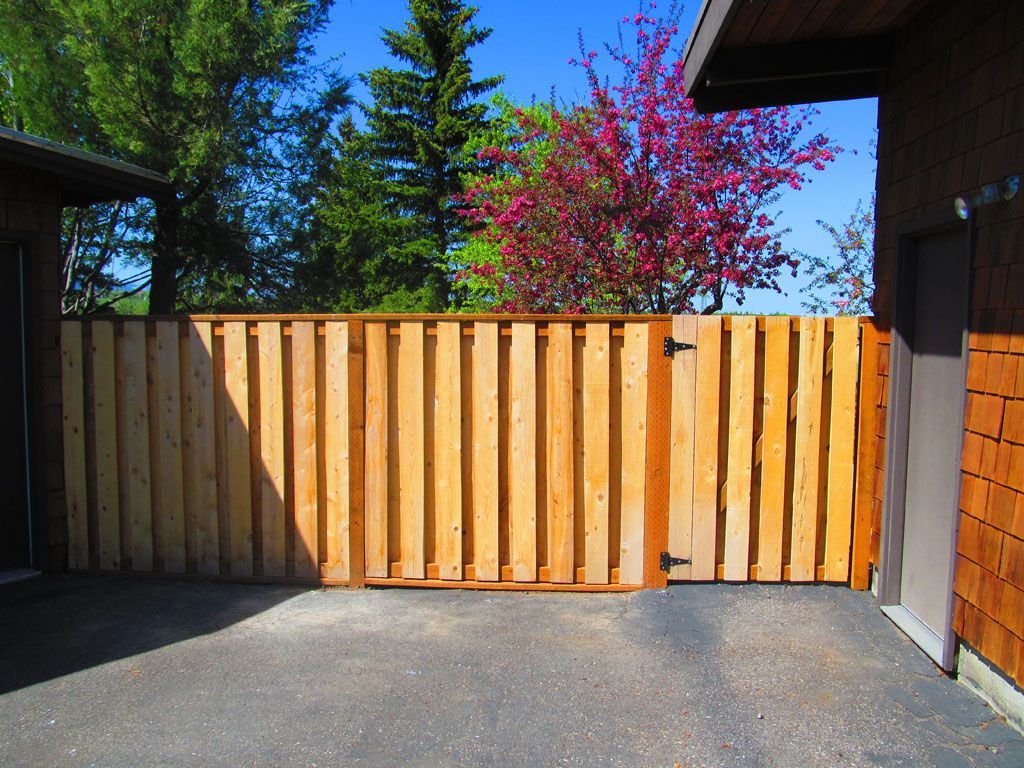A wooden fence with a gate in front of a house.