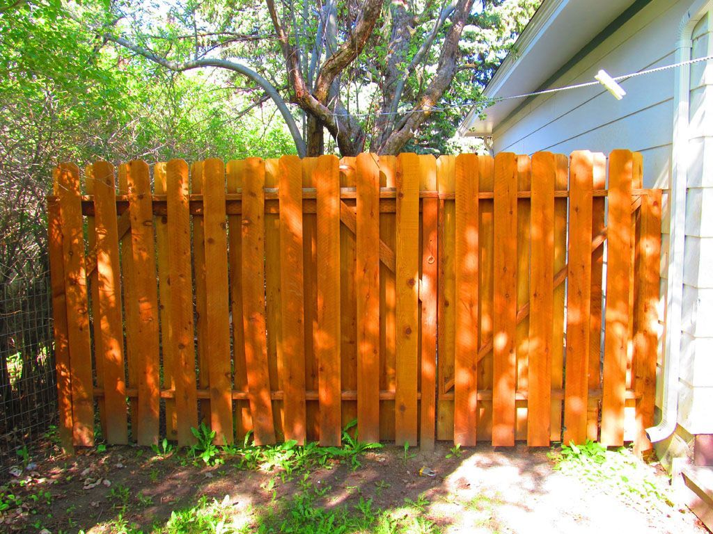 A wooden fence is in the backyard of a house.