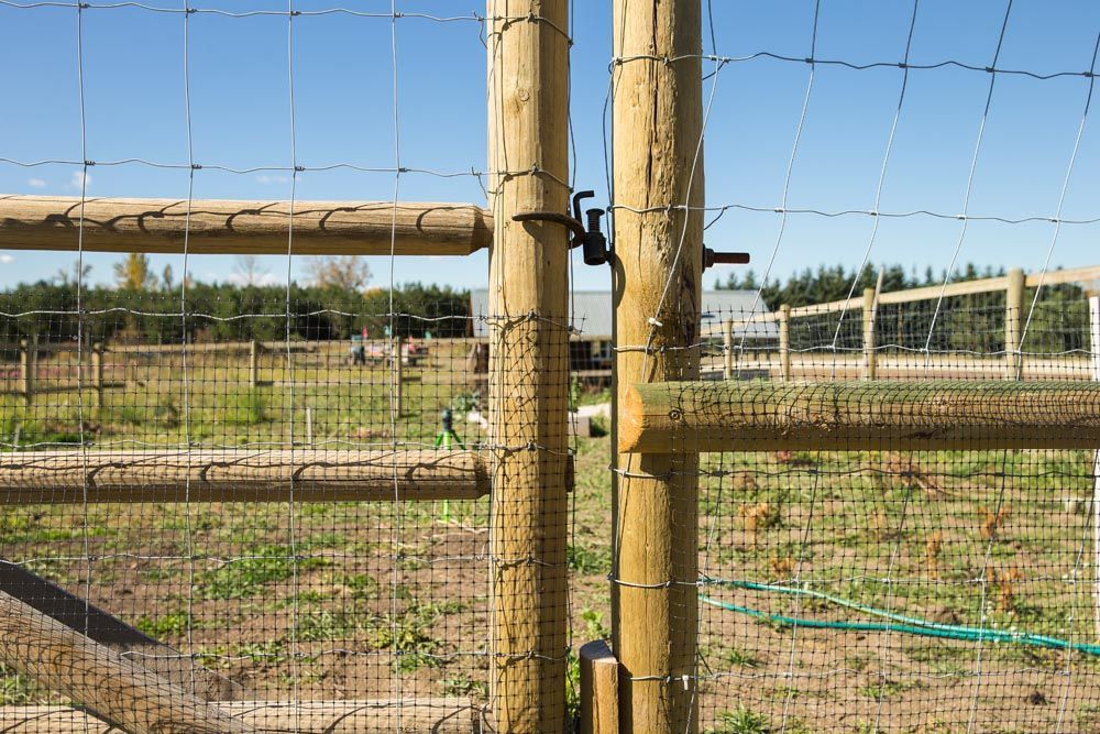 A wooden fence with barbed wire surrounding a field.