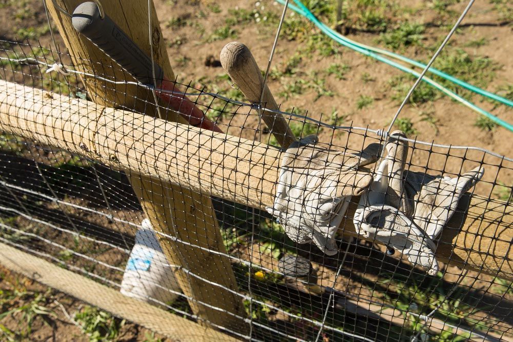 A barbed wire fence with a wooden post and a net.