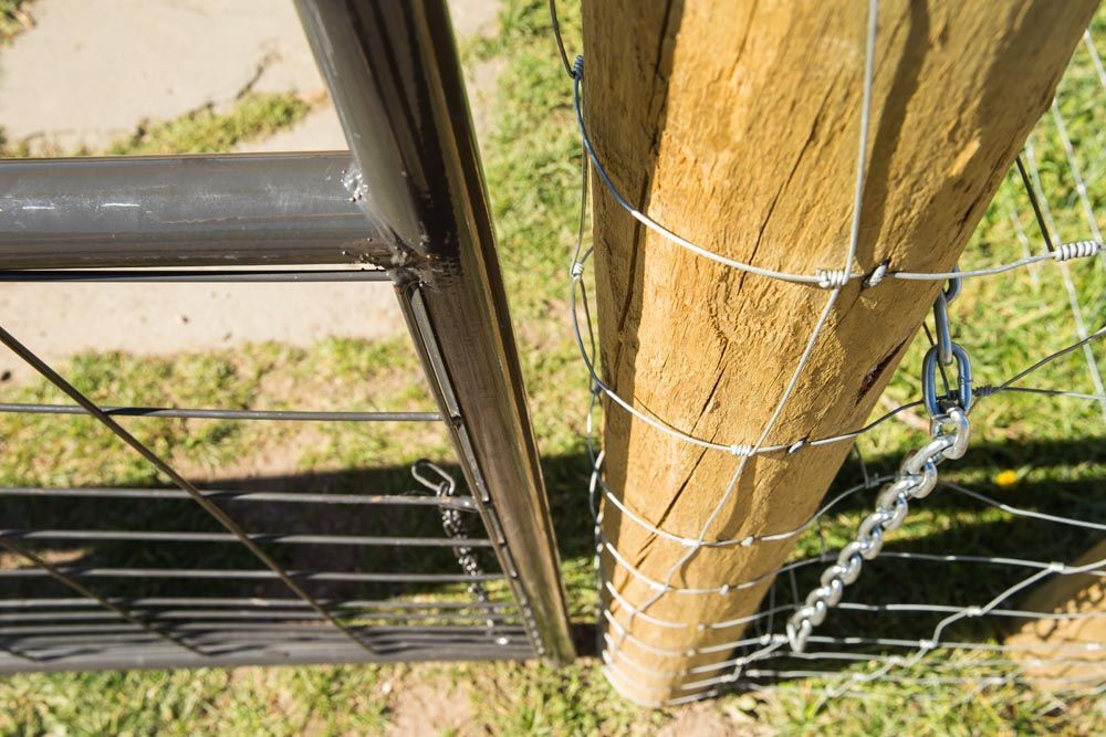 A close up of a fence with a wooden post and barbed wire.