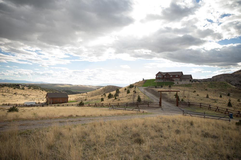 A large house is sitting on top of a hill in the middle of a field.