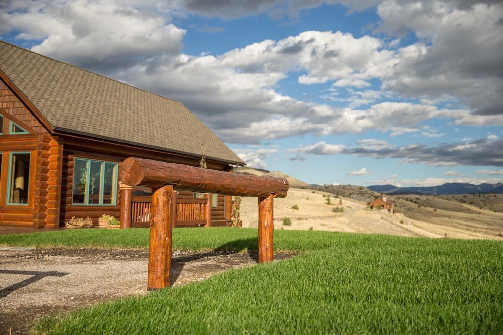 A log cabin is sitting on top of a lush green hillside.